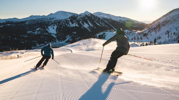 TH_ThomasSobian_Piste_zweiSkifahrer_See_Sonne TH_ThomasSobian_Piste_zweiSkifahrer_See_Sonne